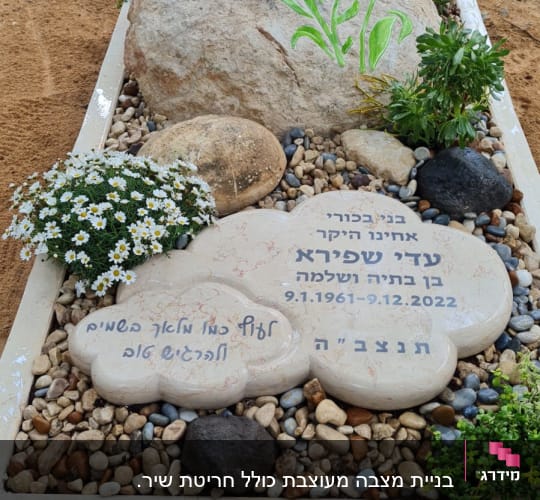קבר עם אבן גדולה ופרחים צבעוניים